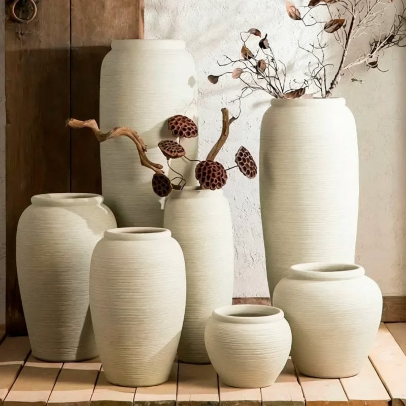 a collection of white ceramic vases arranged on a wooden surface. The vases vary in size and shape, creating a visually appealing display.