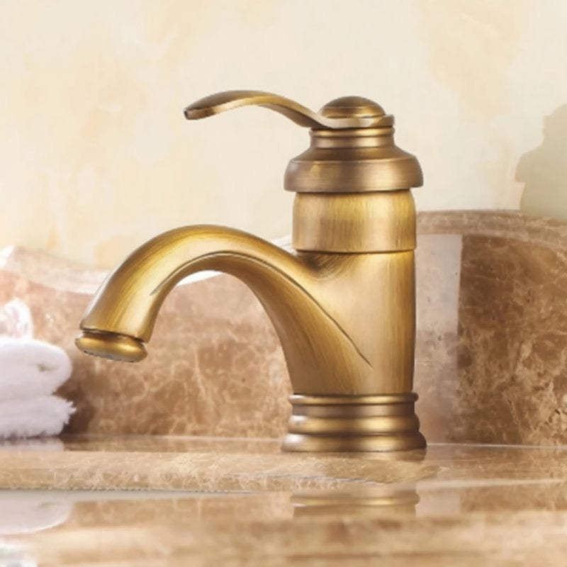 A gold-colored bathroom faucet with a curved spout and a small handle is shown against a marble countertop.