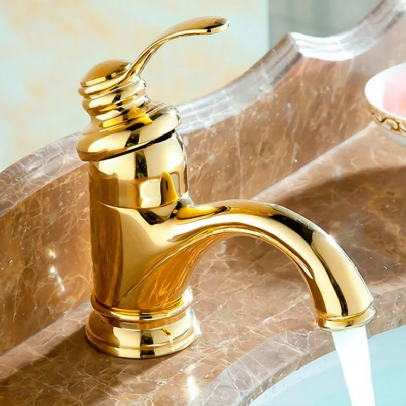 A shiny gold faucet with a curved spout is shown on a marble countertop.